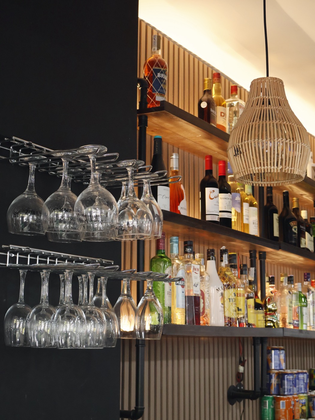 Copas colgadas sobre la barra junto a las estanterías de botellas